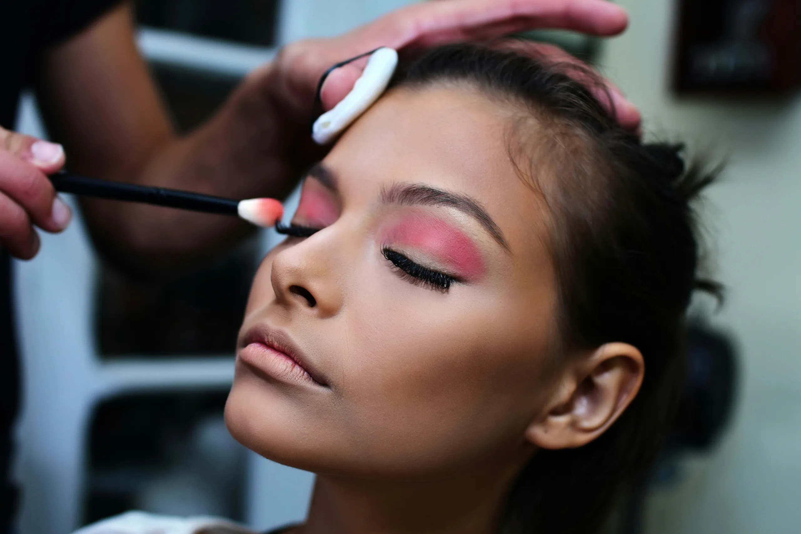 La maquilladora realiza el maquillaje de ojos de una clienta en el salón