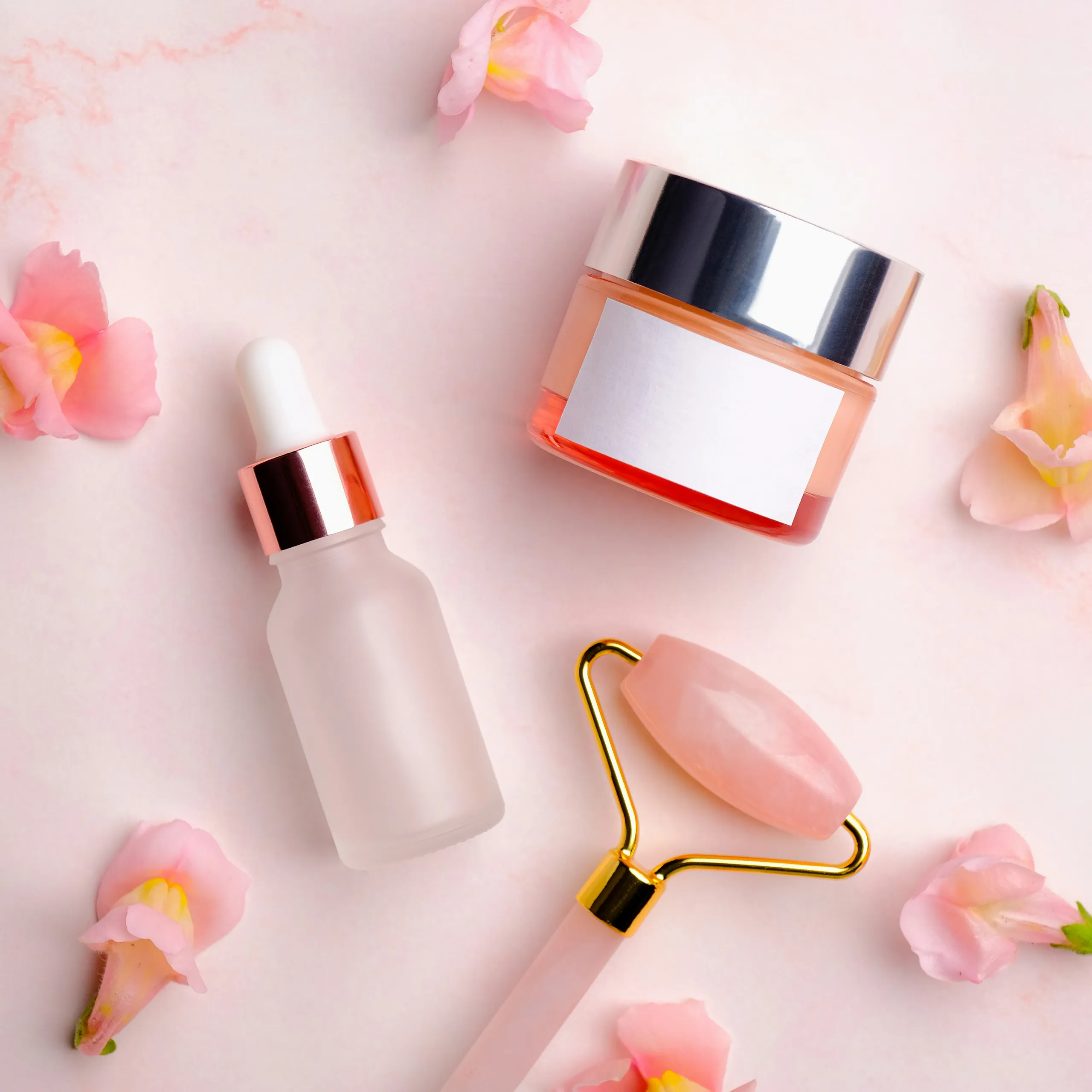 Cosméticos de cuidado con rodillo facial de rosa sobre fondo pastel
