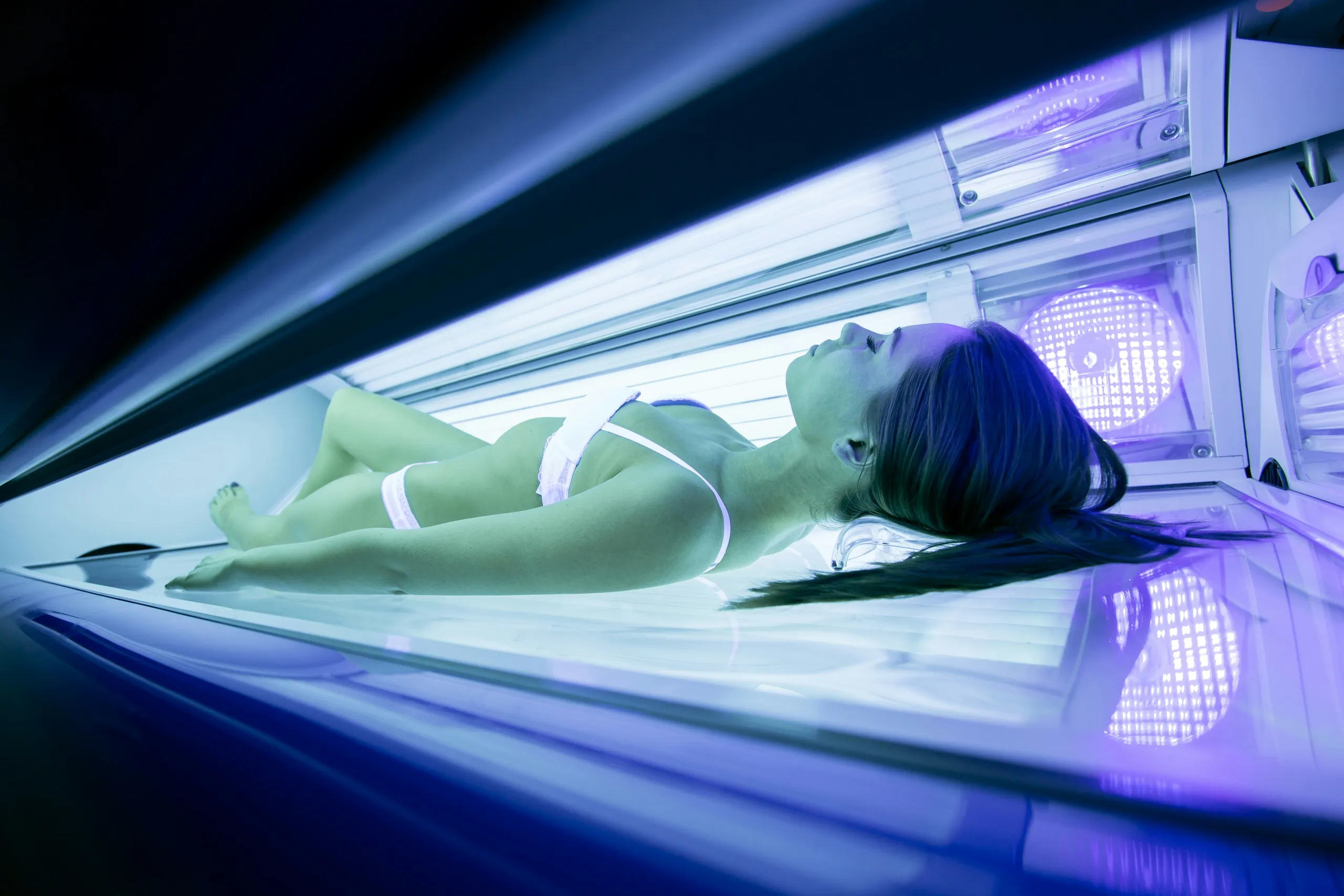 Mujer bronceándose en el solárium bajo la luz azul de las lámparas